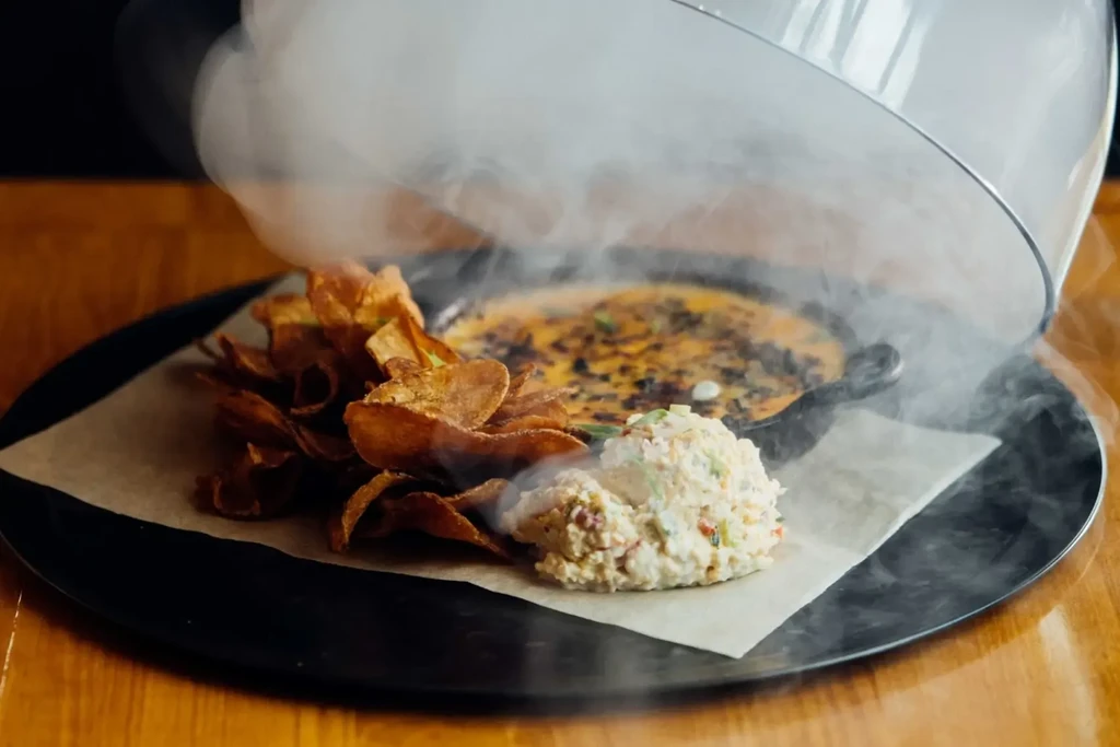 Appetizer with chips, creamy salad, and smoking cheesy dip.