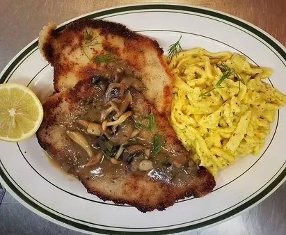 Fried cutlet with mushroom gravy, spaetzle, and lemon slice.