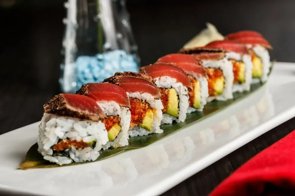 Eight pieces of tuna and avocado sushi on a white plate.
