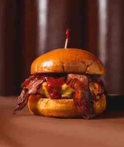 Gourmet burger with a brioche bun, cheese, sauce, and bacon.