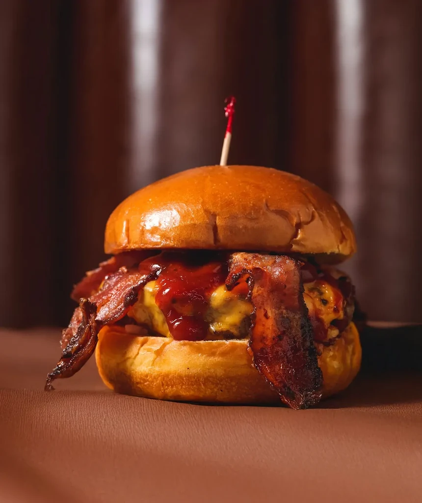 Gourmet burger with bacon, melted cheese, and a brioche bun.