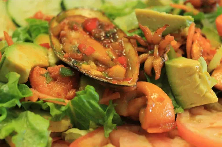 Close-up, high-angle shot of a colorful seafood salad with a mussel.