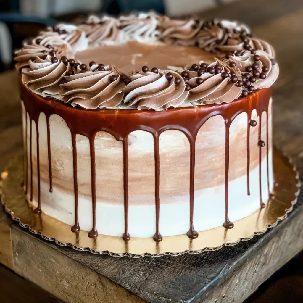 Round ombre cake with chocolate ganache drips and piped frosting.