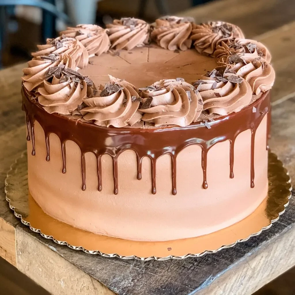 Chocolate cake with ganache, frosting swirls, and chocolate shavings.