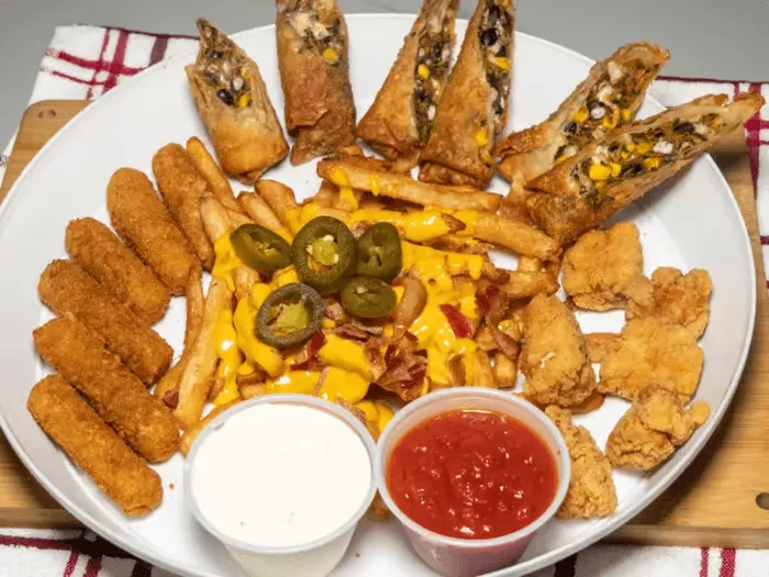 A plate of fries with cheese, bacon, jalapeños, and other fried foods.