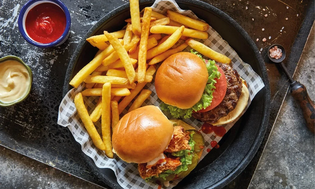 Burgers, fries, ketchup, and sauce served in a black skillet.