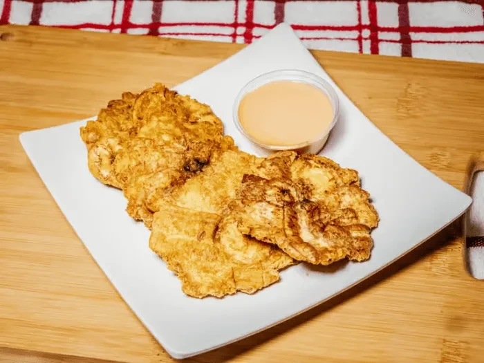 Fried plantains with dipping sauce on a rectangular white plate.