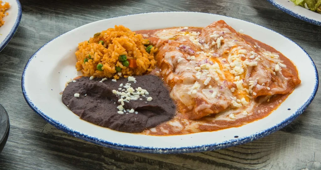 Plate of enchiladas, Mexican rice, and refried black beans.