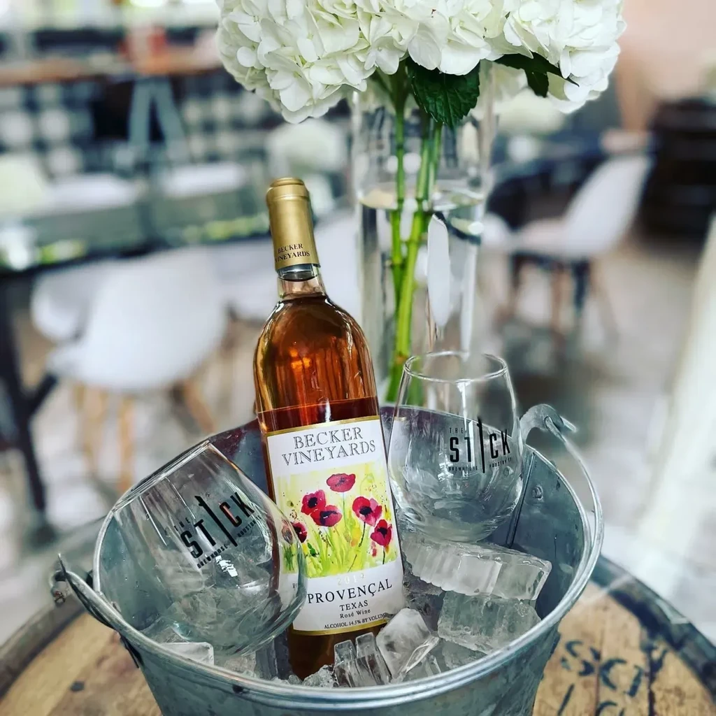Rosé wine bottle and branded glasses chilled in an ice bucket.