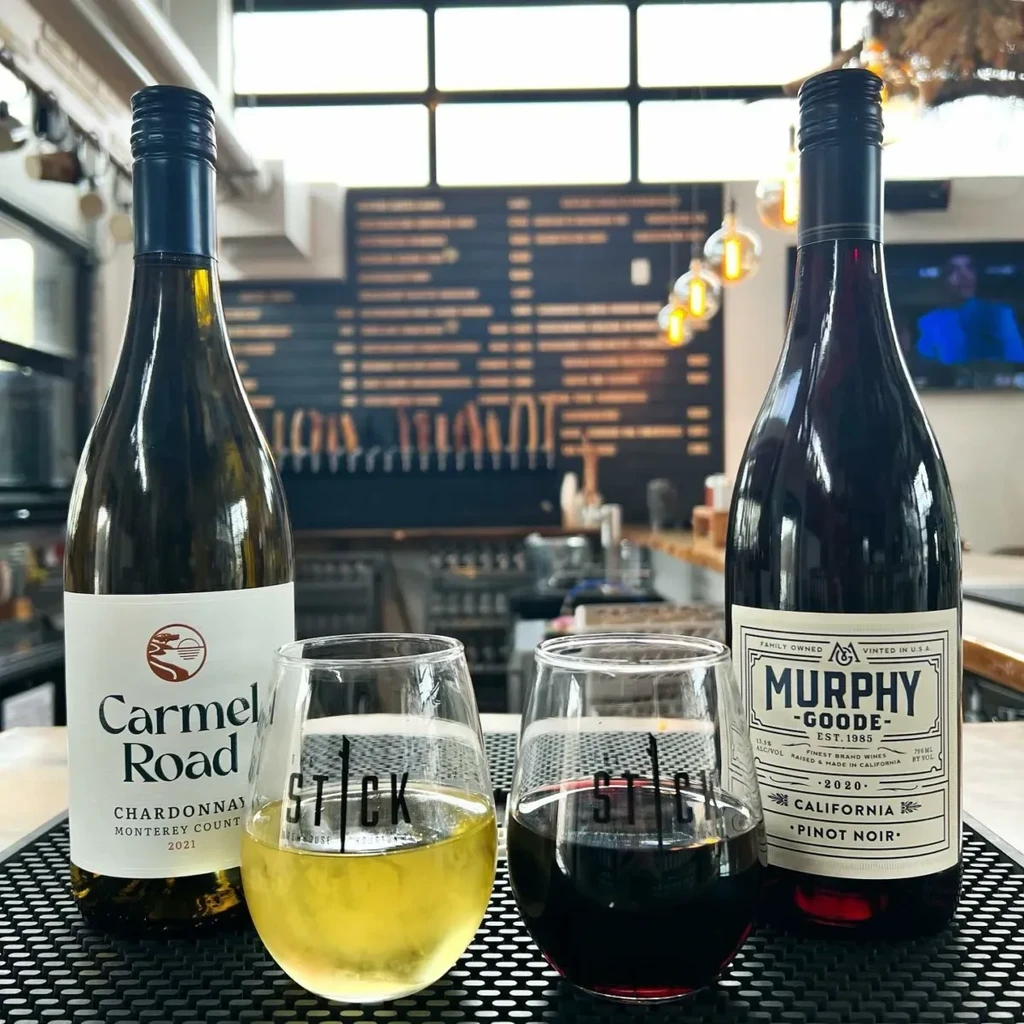 Wine bottles and glasses of white and red wine at a bar.