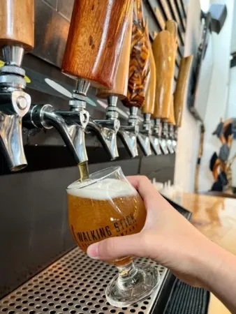 Hand filling a glass with beer from a tap at a bar.
