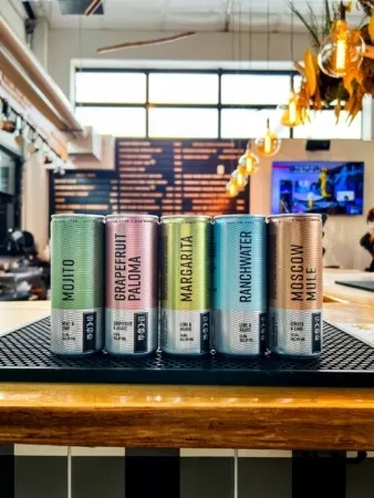 Five canned cocktails on a bar counter in a modern bar.