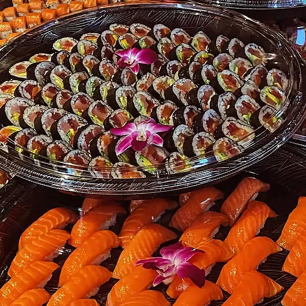 Trays of maki rolls and salmon nigiri with orchid garnish