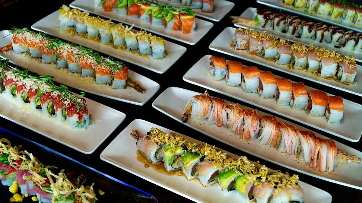 Multiple specialty sushi rolls plated on white rectangular dishes