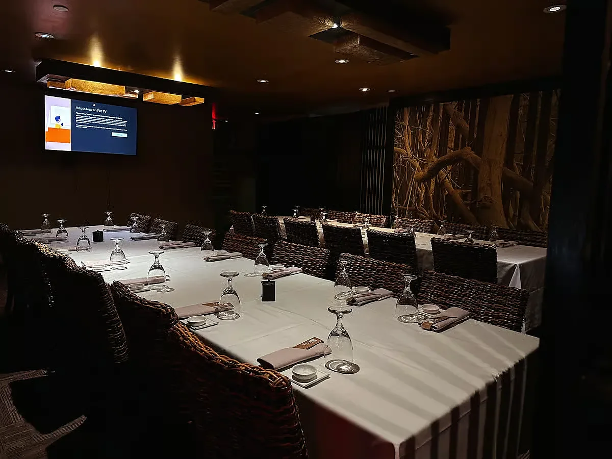 Private dining room with long white-linen table and wicker chairs