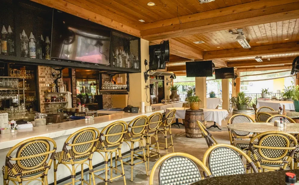 Interior of a well-lit restaurant with a marble bar and dining tables.