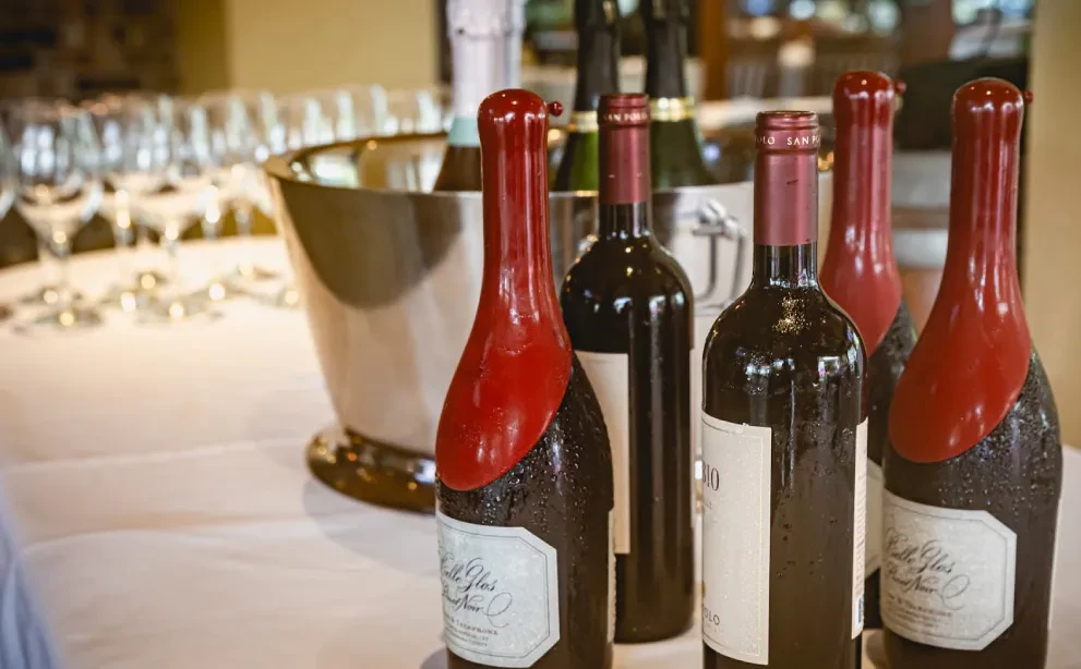 Wine bottles with red wax seals on a white tablecloth.