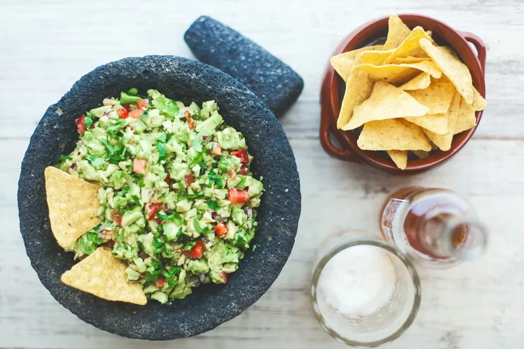 Top-down view of guacamole in a molcajete with tortilla chips.