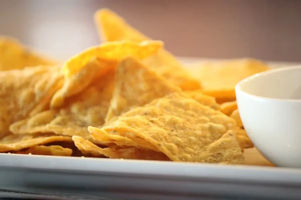 Close-up of golden tortilla chips on a white rectangular plate.