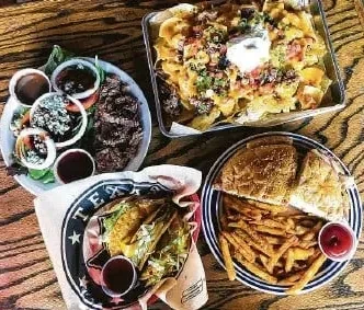 Overhead view of a table laden with nachos, steak salad, tacos, and a burger.