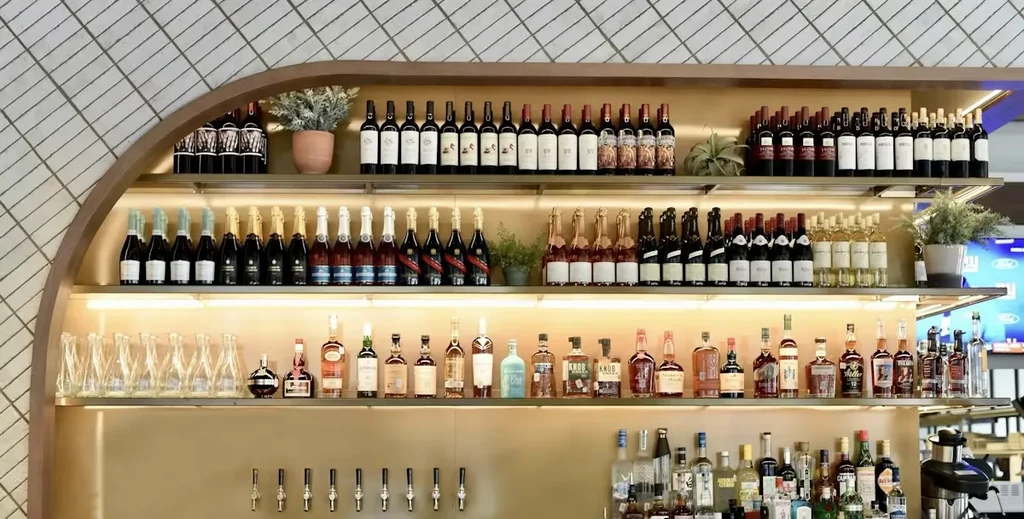 Well-lit bar shelving unit displaying various alcoholic beverages and plants.