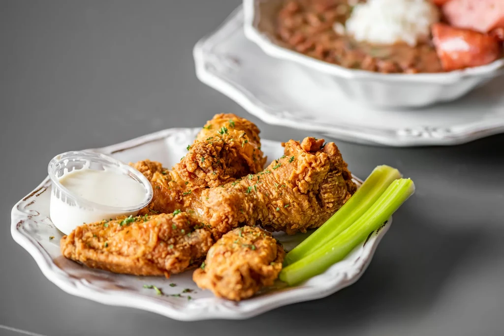 Fried chicken, dipping sauce, and celery on an ornate plate.