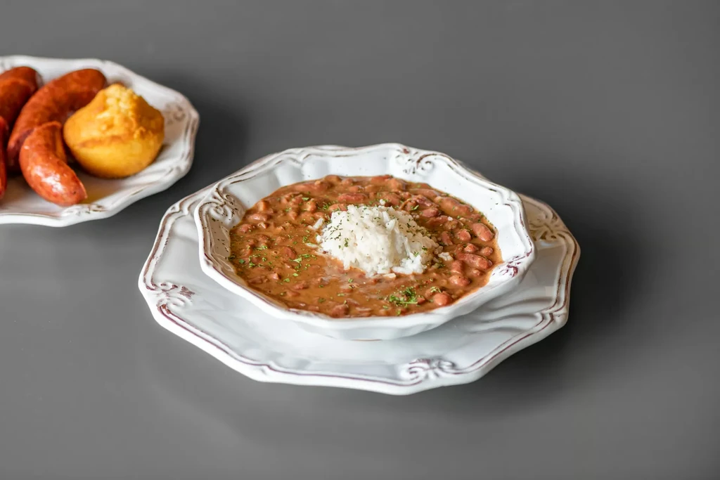 Two plates of food: red beans and rice, sausages and cornbread.
