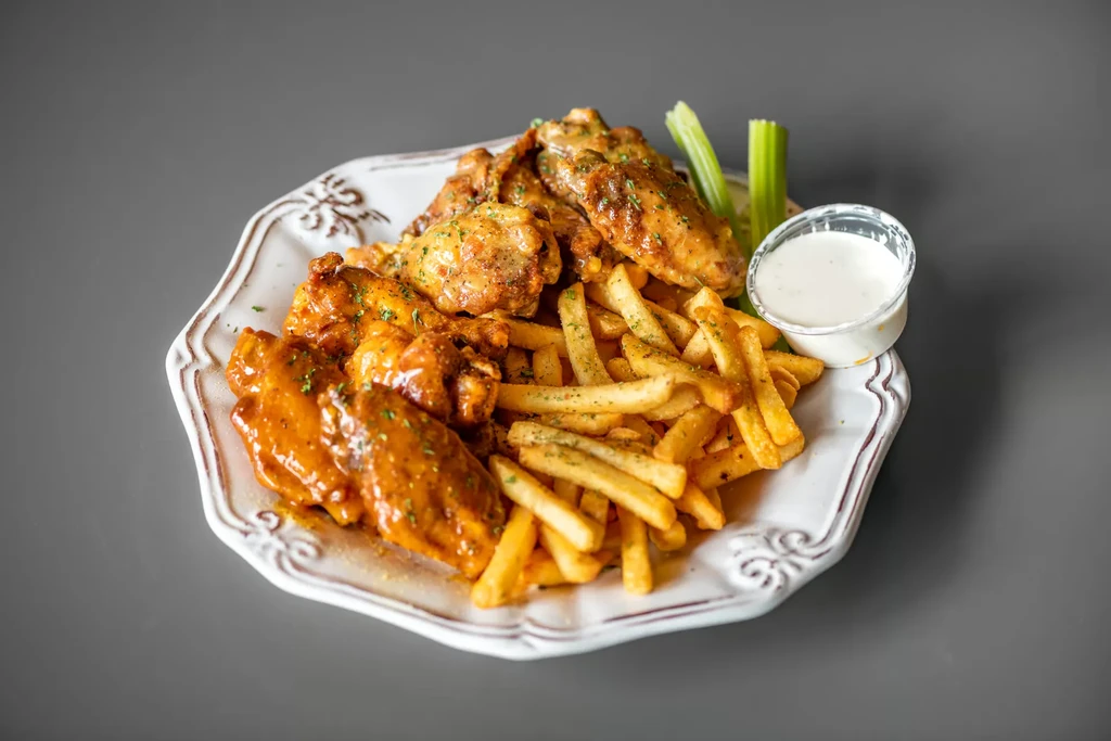 Plate of chicken wings, french fries, dipping sauce, and celery.