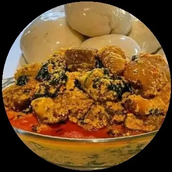 Close-up of a bowl of stew with meat, fish, and greens.