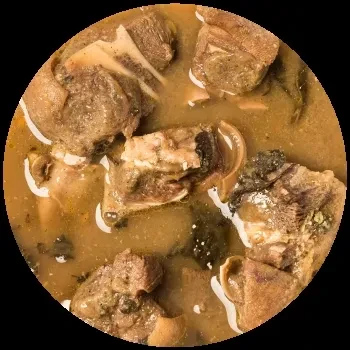 Close-up of a meat stew with bone, vegetables, and murky broth.