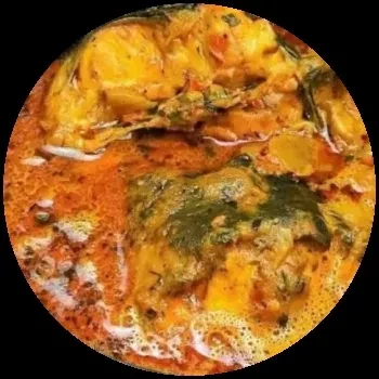 Close-up of fish or poultry curry with dark green leafy vegetables.