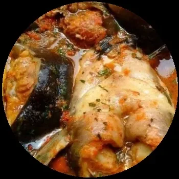 Close-up, top-down view of fish stew with vegetables and herbs.