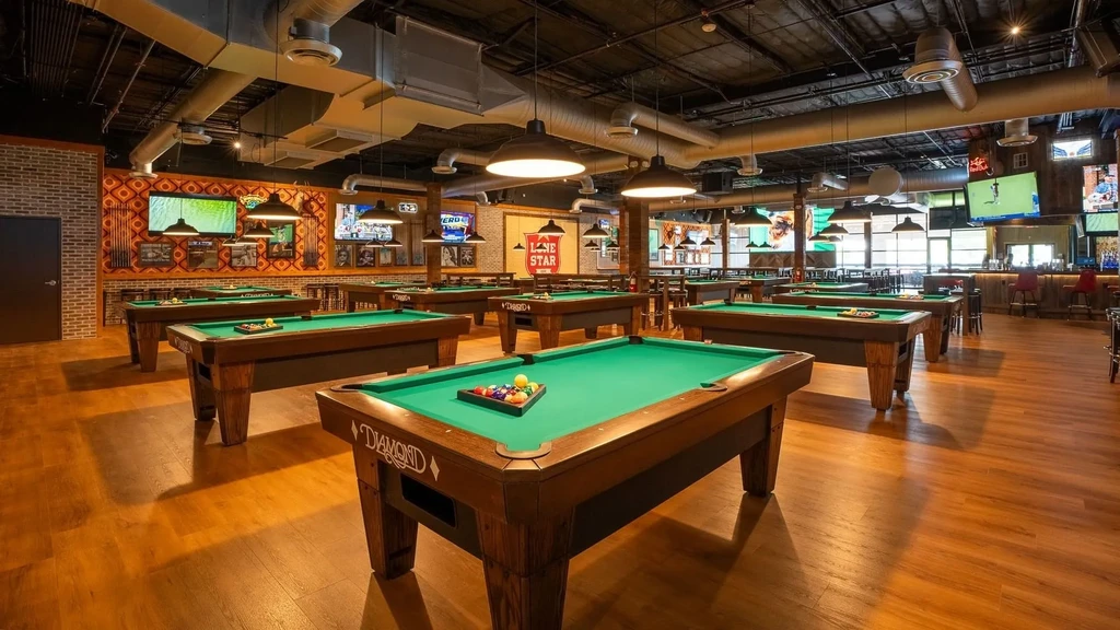 Spacious bar and pool hall with numerous green-felt pool tables.
