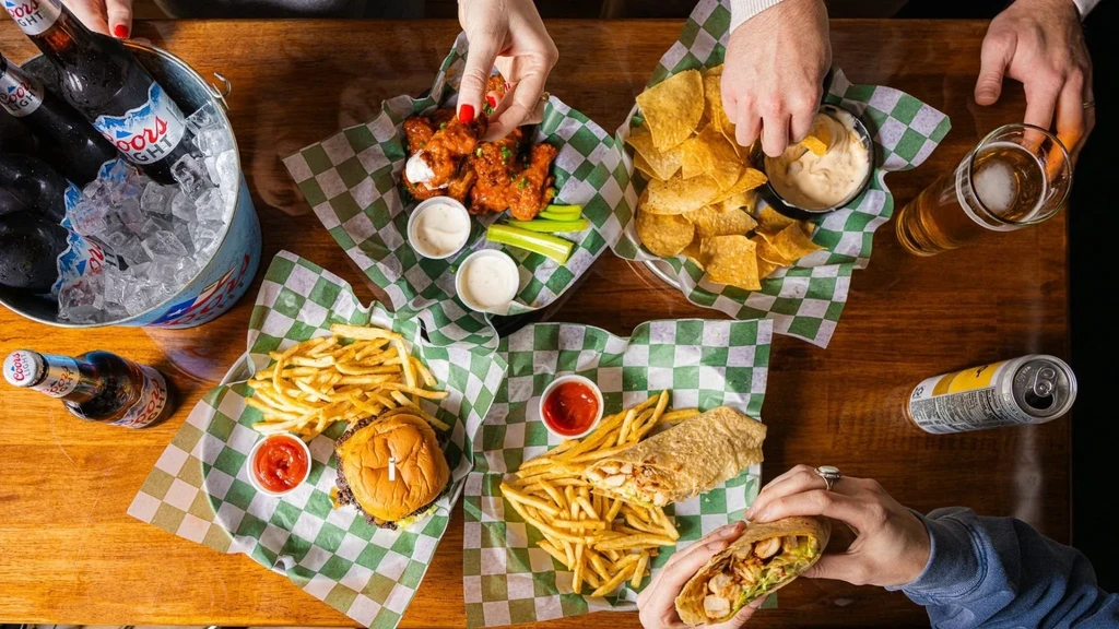 Top-down view of a wooden table laden with various foods and drinks.