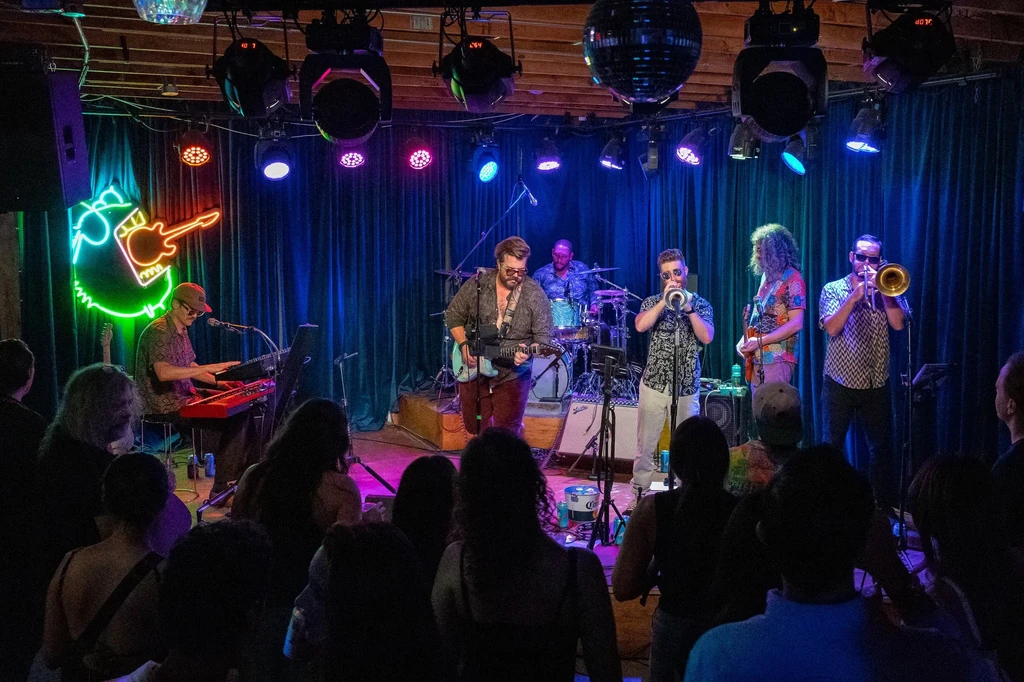 Live band performing on stage with colorful lighting.