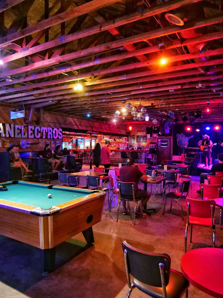 Lively bar with a pool table, band, and colorful lighting.
