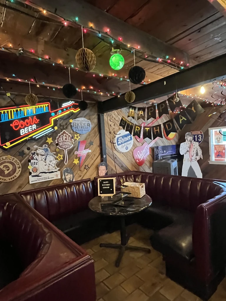 Restaurant booth decorated for a birthday, featuring Elvis cutout and neon sign.