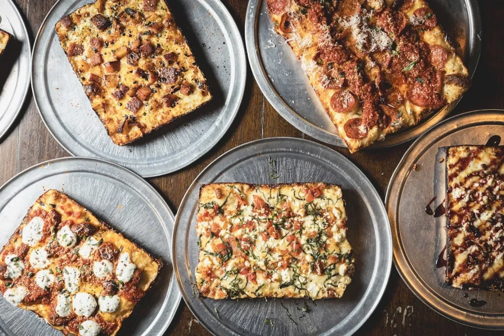 Overhead view of various pizza slices on metal trays.