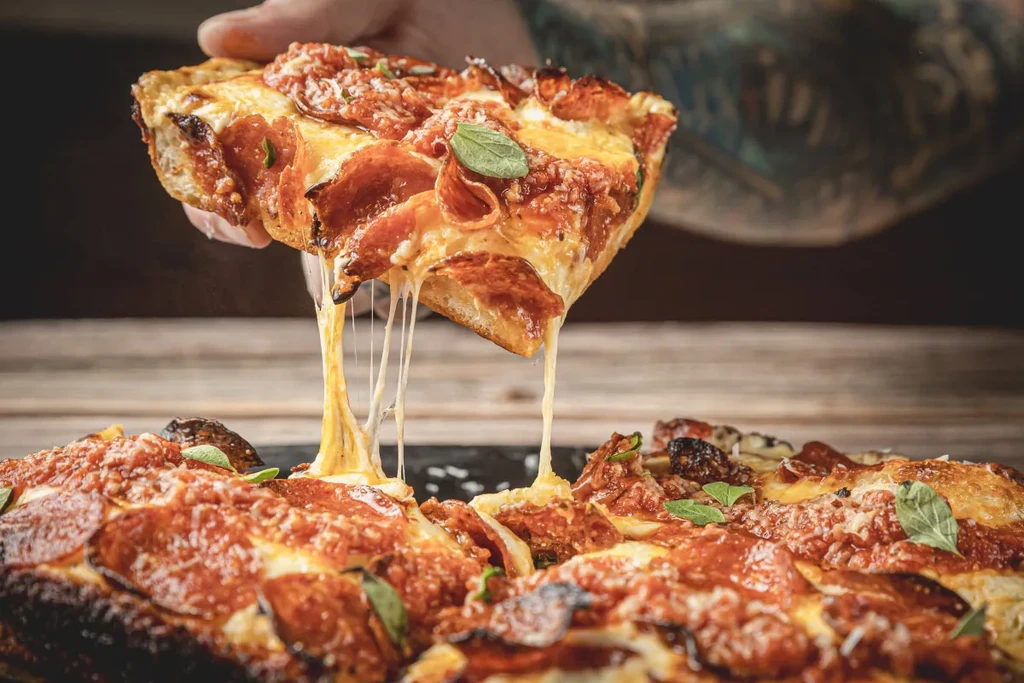 Close-up of a deep-dish pepperoni pizza slice being lifted.