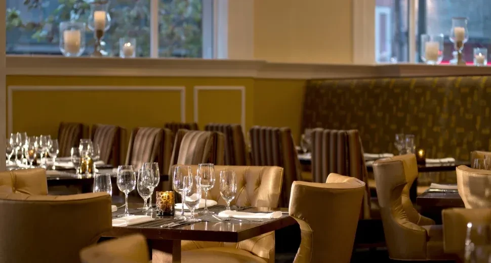 Elegant restaurant dining area with set tables and upholstered chairs.