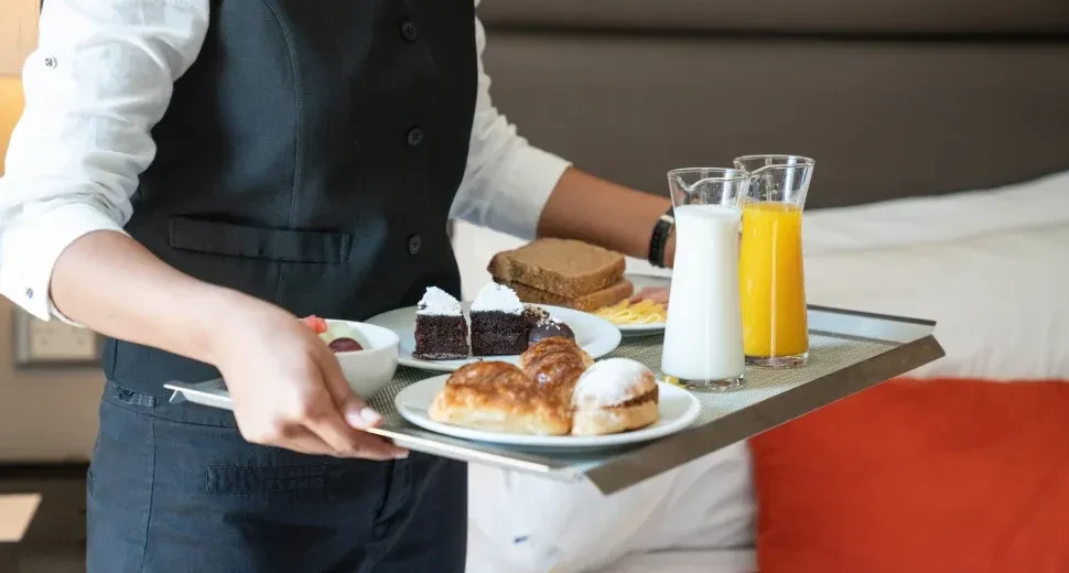 Person holding a tray with breakfast foods and drinks.