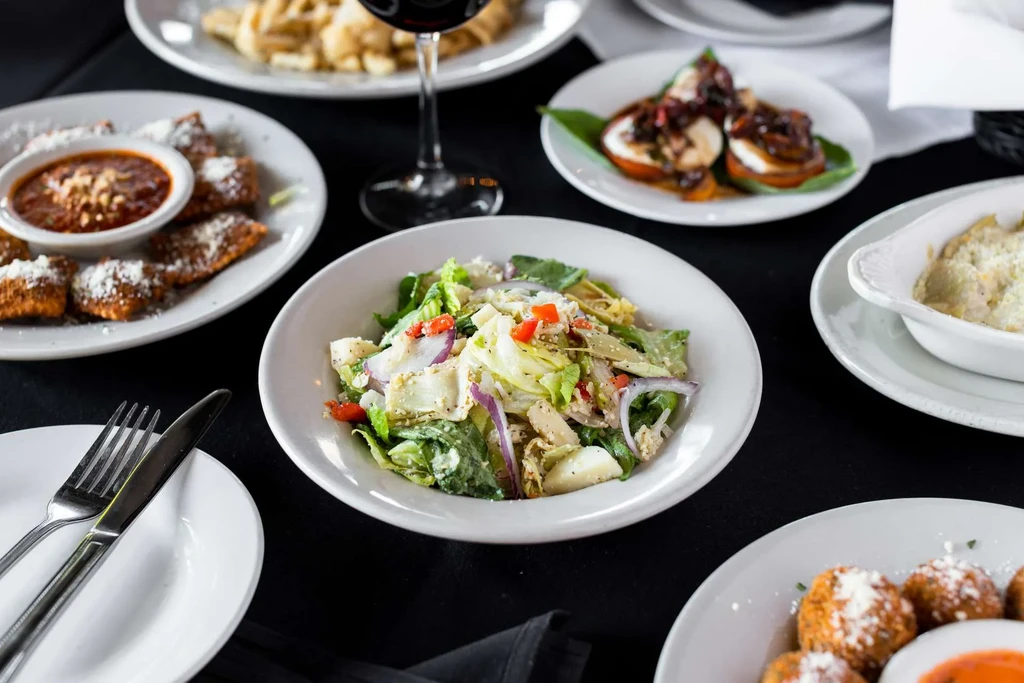 A table set with multiple dishes, including salad, fried items, and roasted tomatoes.