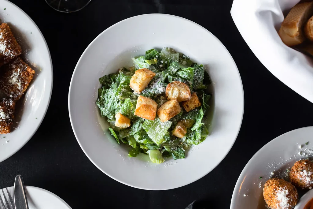 Overhead shot of a table laden with Caesar salad and fried appetizers.