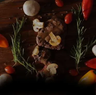 Cooked meat with sauce and mushrooms, garnished with rosemary and vegetables.