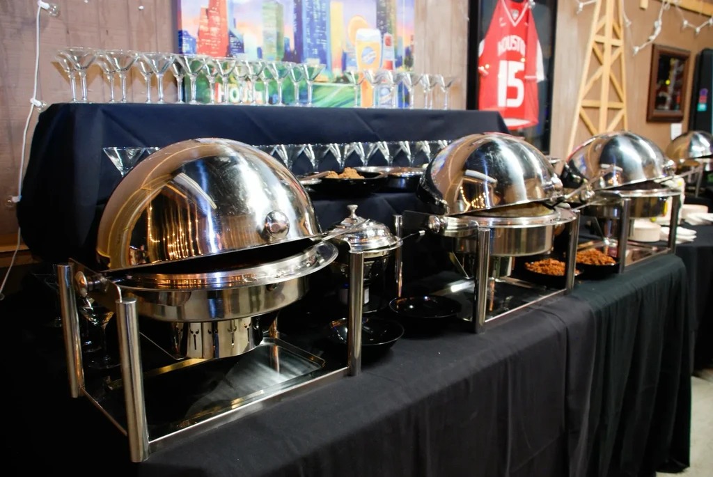 Buffet table with chafing dishes, martini glasses, and cityscape mural.