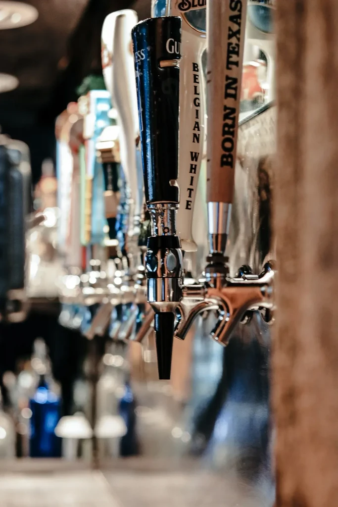 Close-up of three beer tap handles: Guinness, Belgian White, Born In Texas.