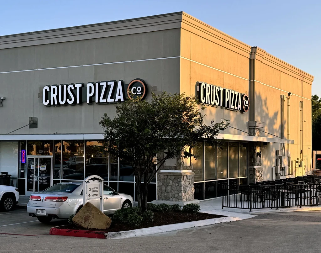 Exterior of Crust Pizza Co. restaurant with outdoor patio.