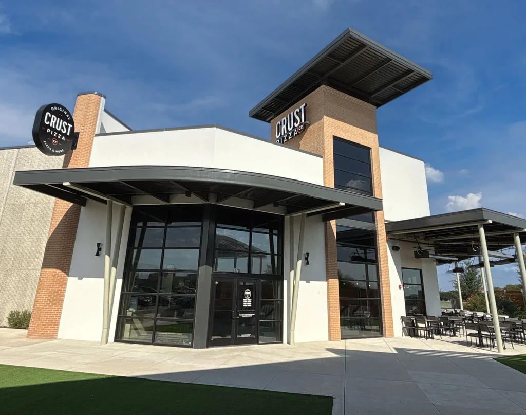 Exterior of modern "CRUST PIZZA CO." restaurant with outdoor patio.