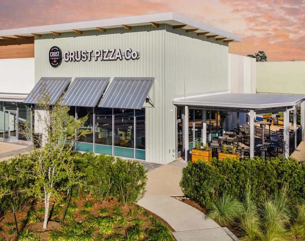 Modern restaurant with outdoor patio under a vibrant sky.