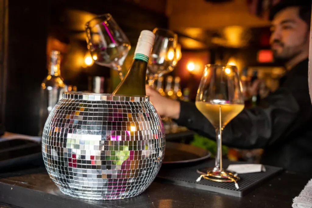 Disco ball ice bucket with white wine, glass, and charm.